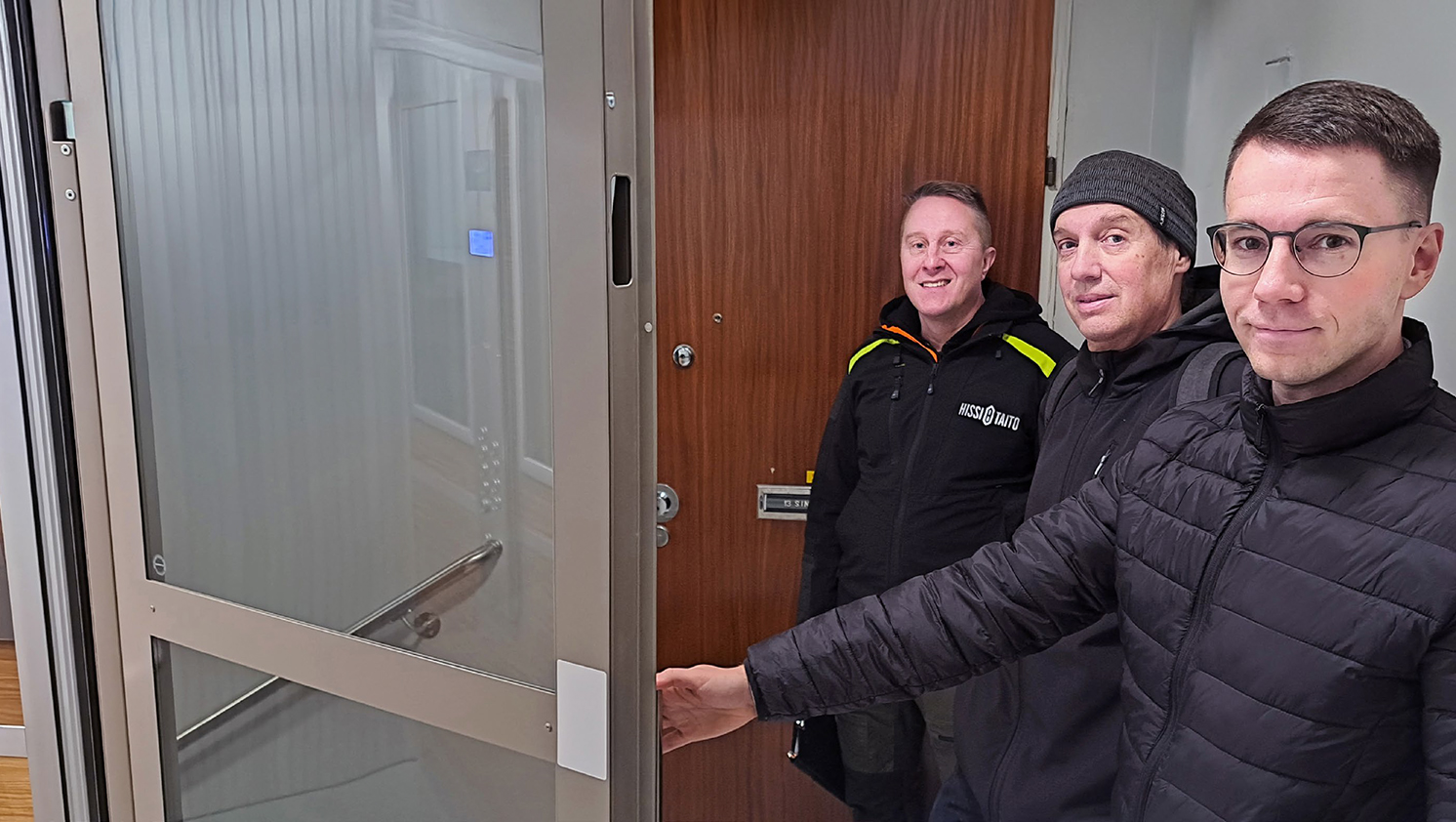 kolme miestä hissin luona